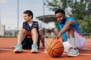 Naklejka premium Two basketball players relaxing after training outdoors on court