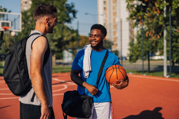 Two male basketball players talking after training outdoors