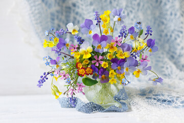 Spring still life with a bouquet of flowers pansies, forget-me-nots, primroses, forget-me-nots, muscari and phlox in a vase on the table, beautiful card.