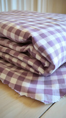 Obraz premium Rolled-up purple gingham fabric on light wood table. Possible use for home decor