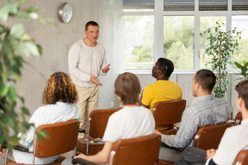 European man leads a lecture in the audience during a meeting of men gays
