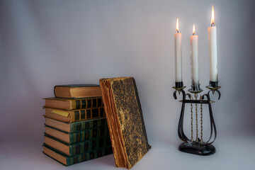 Stack of vintage books with an open cover and antique candelabrum with candles