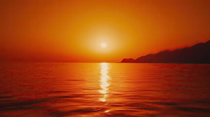 Obraz premium Fiery sunset over calm sea, coastal mountains