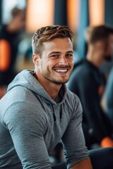 Obraz premium Smiling young man in workout gear enjoying a fitness session at a modern gym during afternoon hours