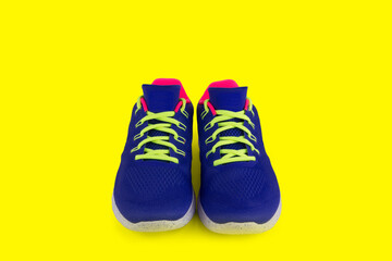 Pair of colorful running shoes on yellow background with copy space