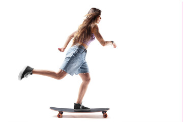 Charming young girl riding a skateboard. Skateboard. Side view. Extreme sports. Young woman riding a skateboard and doing tricks. Sport in action. Isolated