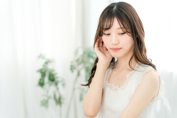 Fototapeta premium ビューティ・スキンケア・ヘアケアイメージのノースリーブ姿の笑顔のアジア人女性（悩む・考える） 