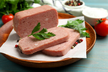 Pieces of tasty canned meat, parsley and peppercorns on light blue wooden table, closeup