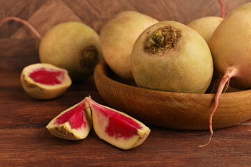 Whole and cut fresh turnips on wooden table, closeup
