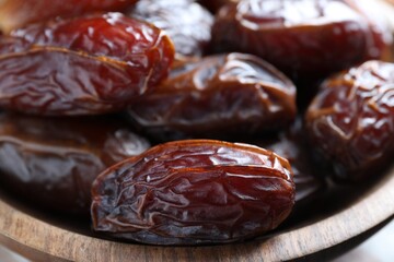 Many tasty dried dates in bowl, closeup