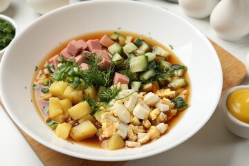 Delicious okroshka soup and ingredients on white table, closeup