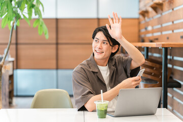カフェで待ち合わせする若いアジア人男性
