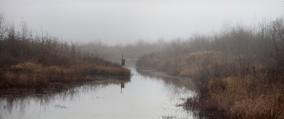 Morning fog on a river between marshes