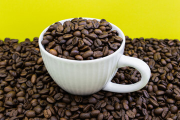 A white coffee cup is filled with coffee beans