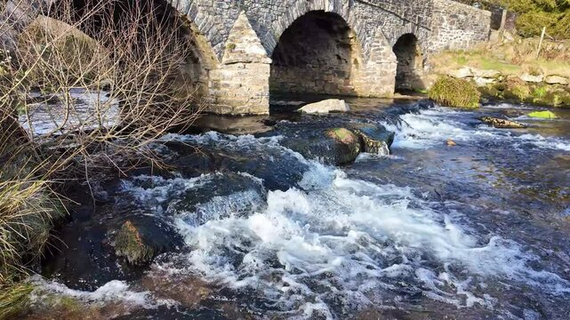 Postbridge Dartmoor Devon England UK. 10.02.2025. Video.  The East Dart River flowing under the road bridge at Postbridge village on Dartmoor Devon UK.