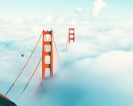 A stunning view of the Golden Gate Bridge emerging from the clouds, creating a surreal and atmospheric scene.