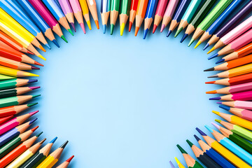 Fototapeta premium Vibrant colored pencils arranged in a heart shape on a light blue background, leaving ample space for text or design elements. Perfect for educational, creative, or artistic projects.