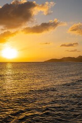 Golden sunset over the ocean with the sun casting a warm glow on the water and silhouetted mountains in the distance. Vieques, Puerto Rico.