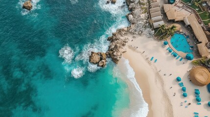 Aerial view turquoise ocean waves crashing on rocky coast, beach resort with pool