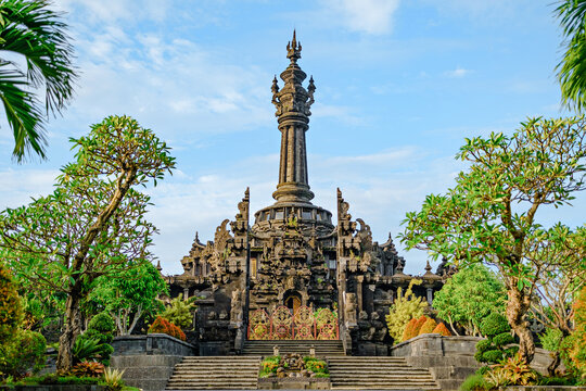Bajra Sandhi Monument in Denpasar, Bali, Indonesia, captured under a bright blue sky with lush greenery surrounding the historical landmark. 