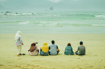 Happy family on the beach. Mother, father, daughter and son and other relatives sitting relaxing on...