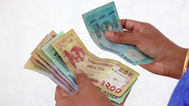 A close-up view of a woman's hand carefully counting Bangladeshi Taka banknotes, including denominations of 1000, 500, 200, and 100 BDT.