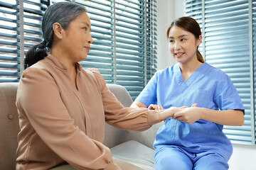 nurse taking care and physical rehabilitation therapy exercise with senior woman on sofa