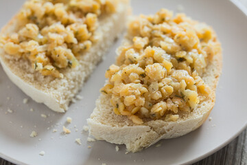 Fresh homemade vegan spread or salad made with split red lentil, onion, garlic and parsley, served on fresh homemade bread on plate (Selective Focus, Focus one third into the right bread)