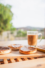 peanut butter and chocolate English muffins with coffee mug on breakfast table with backyard bokeh