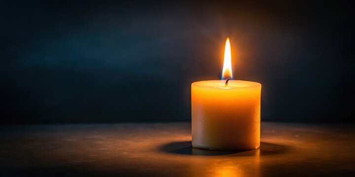 A soft candle flame in a dark environment with a faint glow, creating an intimate ambiance and warm atmosphere
