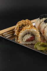 Sushi rolls served on a metallic platter with chopsticks nearby