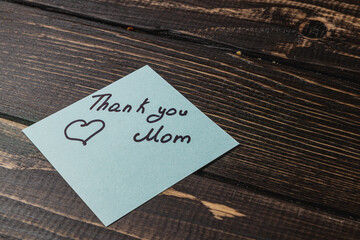 Handwritten note expressing gratitude and love for mom on a wooden table