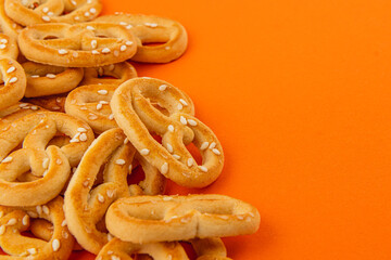 Crispy pretzels scattered on vibrant orange background