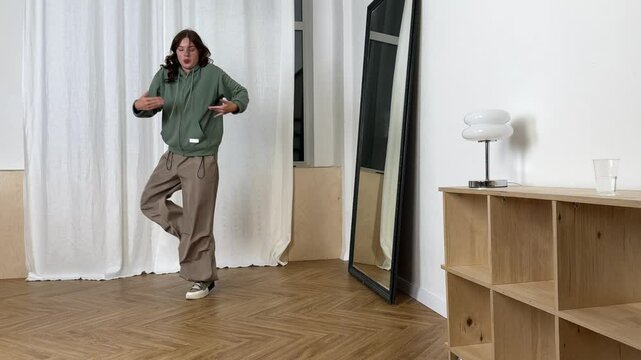 Dancer practices modern dance moves while facing a mirror in a spacious studio environment to enhance skills.