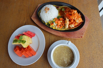 black hotplate rice vegetable fish chicken and meat  dinner with slice fruit