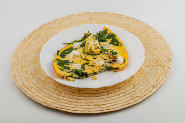 Spinach and cheese omelette served on a woven placemat in a simple setting