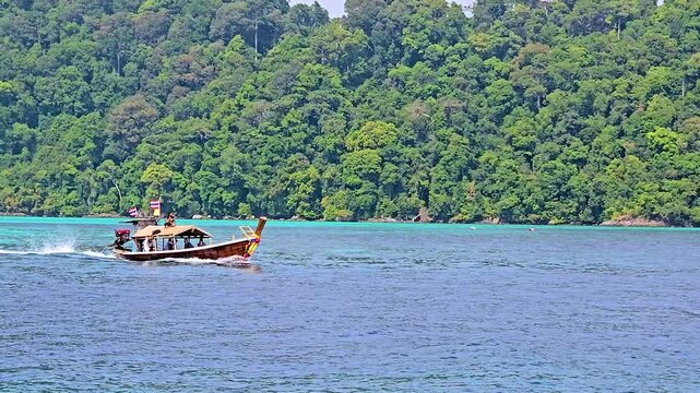 Discover the tranquil beauty of Surin Island in Thailand, where lush greenery meets crystal-clear waters. A traditional boat glides through the serene landscape, inviting adventure and exploration.