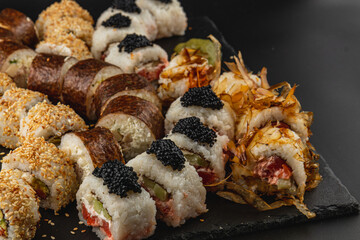 Variety of sushi rolls presented on a black slate platter for casual dining