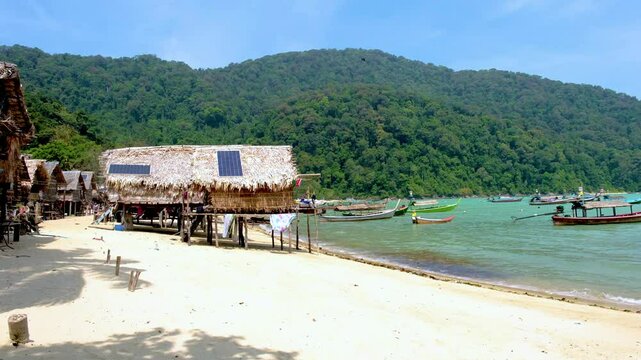 Experience the beauty of Surin Islands sandy shores, vibrant waters, and traditional huts nestled among lush greenery at the traditional Moken village