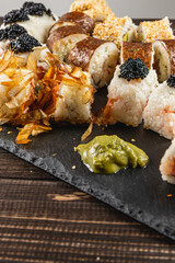 Sushi platter with various rolls and garnishes on a dark slate board