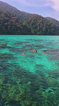 Bright turquoise waters invite adventurers to discover the thriving marine life near Surin Island. people snorkeling on a day trip in Thailand