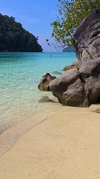 Experience the stunning coastline of Surin Island, Thailand, with its clear turquoise waters, soft sandy beaches, and lush greenery. A tranquil paradise awaits those seeking relaxation and adventure.