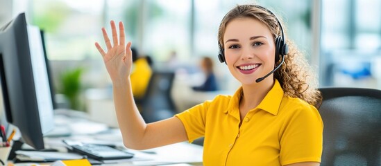 Smiling office worker waves hello, headset on, busy background