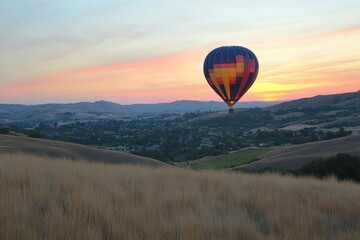 Obraz premium Hot air balloon floats over tranquil valley at sunset, colorful stripes visible. Ideal for travel, adventure, freedom, and serenity themes.