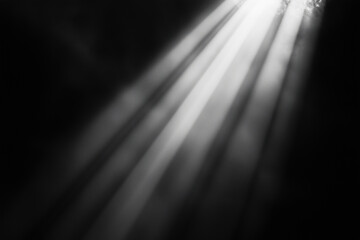  black and white photo of a light shining on a surface. The light is casting shadows and creating a sense of depth and dimension. The photo has a moody and atmospheric feel