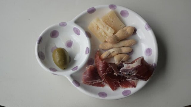Delicious plate of tapas with olives, jamon, cheese, and colines served on a dish