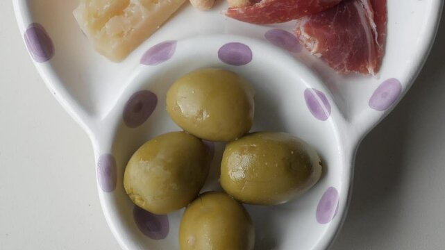 Olives served as part of a Spanish tapas plate with jamon, cheese, and colines