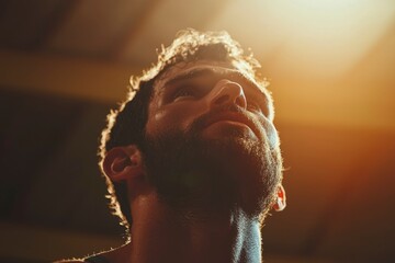 Focused man with glowing face looks up in a gym. Success portrait of dedication