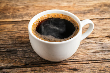 Cup of steamy hot black coffee with warm steam cloud in a white mug