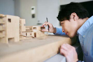 建築の模型を作りながら考える建設コンサルタントの1人の男性